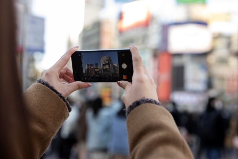 Person capturing DOOH screens in a busy city, illustrating DOOH Audience Insights in real-world environments